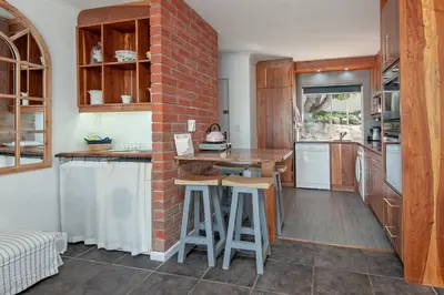 a kitchen with a brick wall and a counter with stools at 63 Whalerock Estate in Hermanus