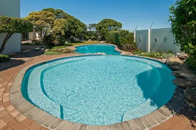 a large swimming pool with a brick walkway around it at 63 Whalerock Estate in Hermanus