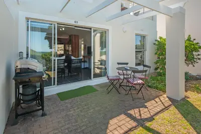 a patio with a grill and a table and chairs at 63 Whalerock Estate in Hermanus