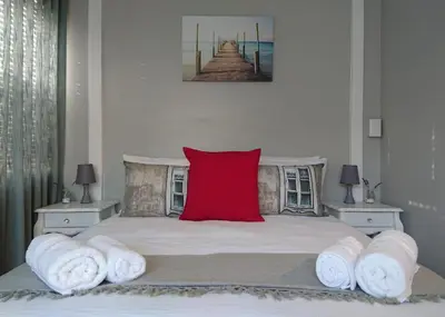 a bedroom with a bed with a red pillow on it at Hamilton Garden Suites in Parklands