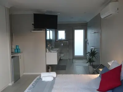 a bathroom with a bed and a sink and a shower at Hamilton Garden Suites in Parklands