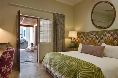 a bedroom with a large bed and a mirror at The Coach House in Franschhoek