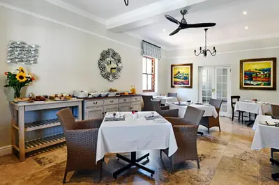 a restaurant with tables and chairs and a kitchen at The Coach House in Franschhoek