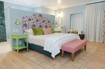 a bedroom with a large bed and a pink stool at Last Word Franschhoek in Franschhoek