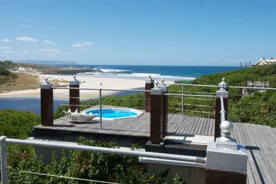 a wooden deck with a view of the beach at Kennedys Beach Villa in Hermanus