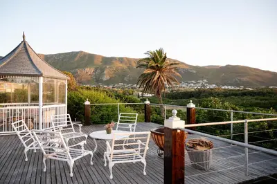 a deck with chairs and a table and a gazebo at Kennedys Beach Villa in Hermanus