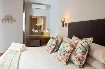 a bedroom with a bed with floral pillows and a mirror at Avemore Vredehof No 3 full back up power in Stellenbosch