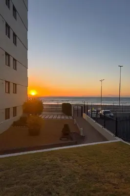 a sunset behind a building and the beach at Luxurious Beach Front in Strand