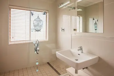 a white bathroom with a sink and a mirror at Luxurious Beach Front in Strand