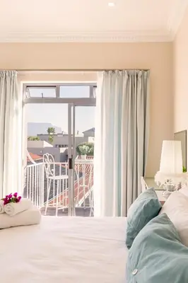 a bedroom with a bed and a balcony at Atlantic Beach Villa in Cape Town