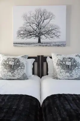 two beds in a bedroom with a tree on the wall at Atlantic Beach Villa in Cape Town