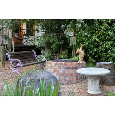 a cat statue sitting on a brick wall next to a bench at Languedoc in Stellenbosch