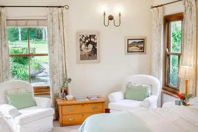 a bedroom with two chairs and a bed and a window at Languedoc in Stellenbosch