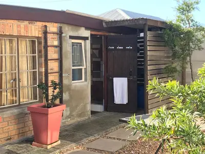 a house with a potted plant in front of a door at The Yard in Gordonʼs Bay