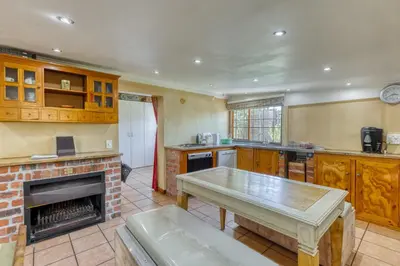 a kitchen with a fireplace and a table in it at The Yard in Gordonʼs Bay
