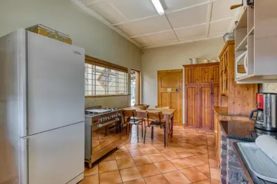 a kitchen with a refrigerator and a table with chairs at The Yard in Gordonʼs Bay