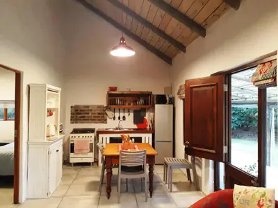 a kitchen with a table and a stove and a refrigerator at The Cottage at Nuwejaarsrivier Farm in Kleinmond