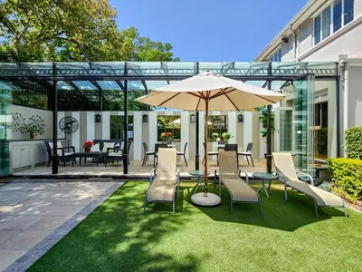 a patio with an umbrella and chairs on the grass at Roodenburg House in Cape Town