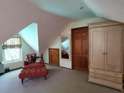 a living room with a red chair and a cabinet at Le Manoir de Brendel in Franschhoek