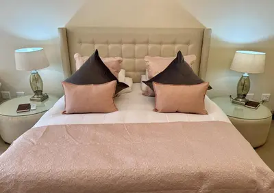 a bed with pink and black pillows and two lamps at Le Manoir de Brendel in Franschhoek