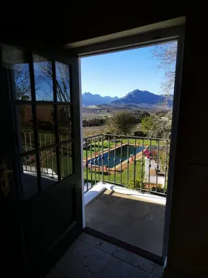 a door leading to a balcony with a view of a pool at Gemoedsrus Farm in Stellenbosch