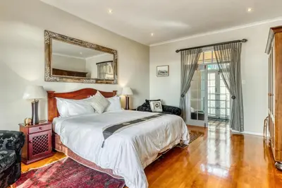 a bedroom with a large bed and a mirror at Manor on the Bay in Gordonʼs Bay