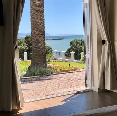 an open door to a patio with a palm tree at Manor on the Bay in Gordonʼs Bay