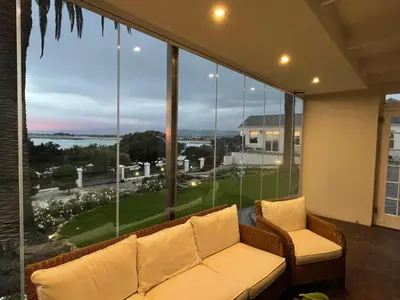 a living room with a couch and a large window at Manor on the Bay in Gordonʼs Bay