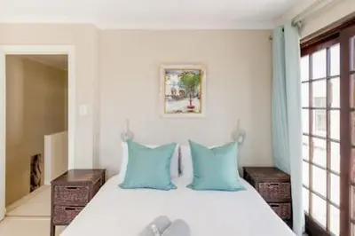 a bedroom with a bed with blue pillows at Nansen Place in Cape Town