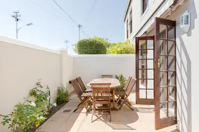 a patio with a table and chairs on a white wall at Nansen Place in Cape Town