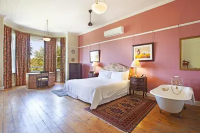 a bedroom with a bed and a tub in it at Medindi Manor in Cape Town