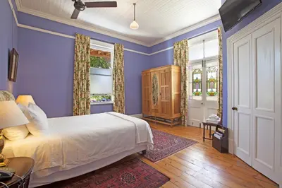 a bedroom with blue walls and a bed and windows at Medindi Manor in Cape Town