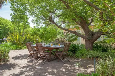 a table and chairs sitting on a patio under a tree at Medindi Manor in Cape Town
