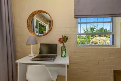 a laptop on a desk in a room with a window at Morgen Guesthouse Somerset West in Somerset West