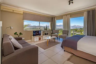a bedroom with a bed and a living room at Morgen Guesthouse Somerset West in Somerset West