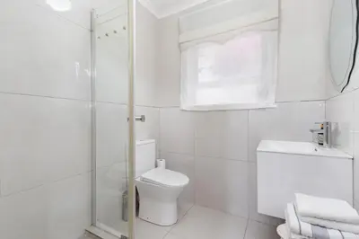 a white bathroom with a toilet and a shower at Cape Goodness in Bellville
