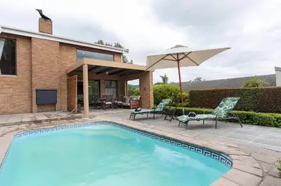 a swimming pool with a patio and an umbrella at Cape Goodness in Bellville