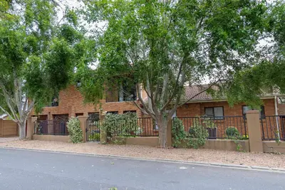a brick building with a fence and a tree at Cape Goodness in Bellville