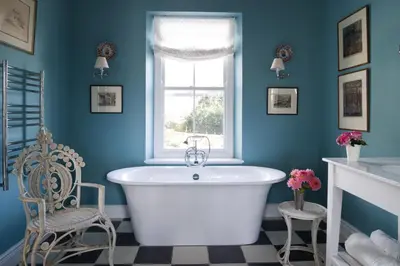 a blue bathroom with a white tub and a window at La Cotte Orchard Cottages in Franschhoek