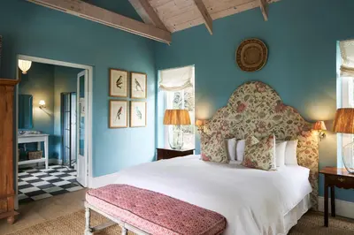 a bedroom with a large white bed and blue walls at La Cotte Orchard Cottages in Franschhoek