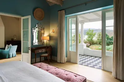 a bedroom with a bed and a door leading to a balcony at La Cotte Orchard Cottages in Franschhoek