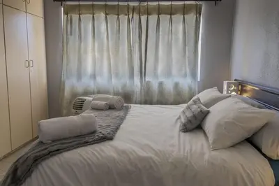 a bedroom with a large white bed with a window at Cape Pine Guest House in Kuilsrivier