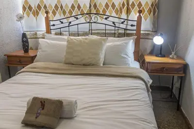 a large bed with white sheets and pillows at Cape Pine Guest House in Kuilsrivier
