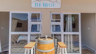 a store front with a barrel and two stools at Sea Breeze Guest House in Bloubergstrand