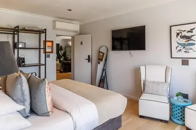 a bedroom with a bed and a chair at The Whale's Tale Guesthouse in Hermanus