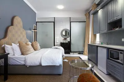 a bedroom with a large bed and a kitchen at Life & Leisure Boutique Guesthouse in Stellenbosch