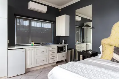 a kitchen with white cabinets and a bed in a room at Life & Leisure Boutique Guesthouse in Stellenbosch