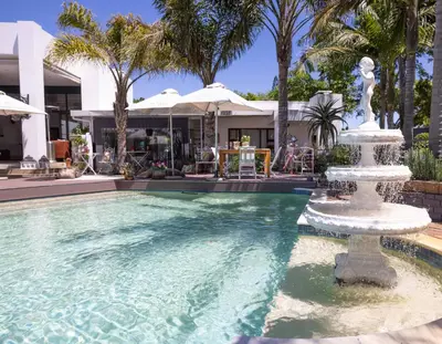 a fountain in a pool in front of a house at Cape Pillars Boutique Hotel in Durbanville