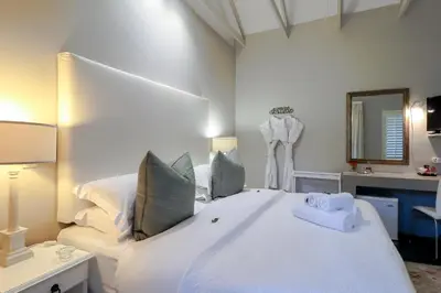a bedroom with a large white bed and a mirror at Hermanus Lodge on the Green - Solar Power in Hermanus