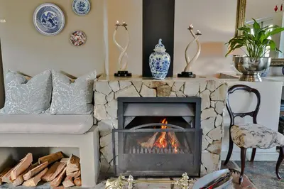 a living room with a fireplace and a couch at Hermanus Lodge on the Green - Solar Power in Hermanus